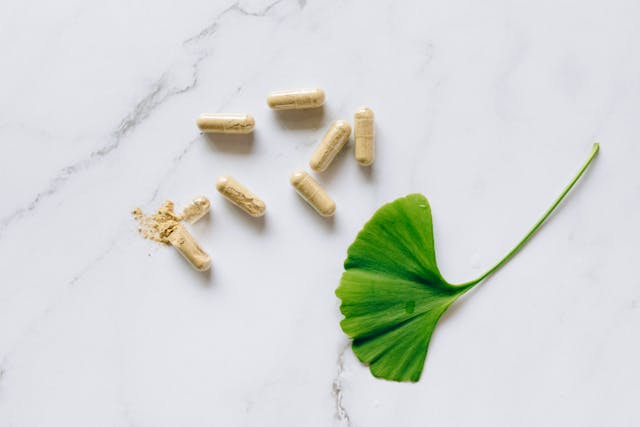 green leaf and pill capsules on a marble background